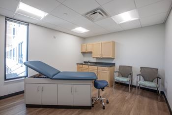 a patient room with a blue exam table and two chairs